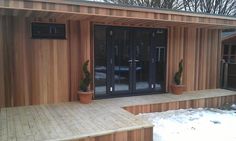 a wooden building with glass doors and steps leading up to the front door in snow