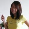 a woman in a yellow shirt is smiling and holding her hand up to the camera