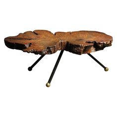 a wooden table with two black legs and a large leaf design on the center piece