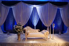 a white couch sitting on top of a table next to a vase filled with flowers