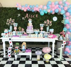 a table topped with lots of balloons and cake on top of a checkered floor