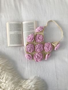 a purse made out of crocheted yarn with pink roses on it and an open book