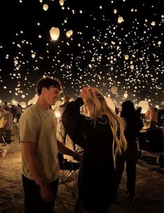 two people looking up at the sky full of lanterns