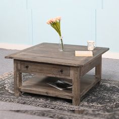 a coffee table with flowers in a vase on it and a rug underneath the table