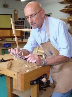 a man working with woodworking tools on a wooden table