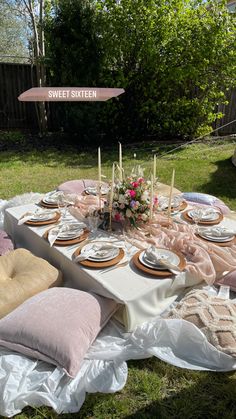 a table set up with plates and candles for an outdoor dinner party in the backyard