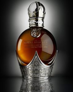 a bottle of royal blacquea on a reflective surface with a crown around it