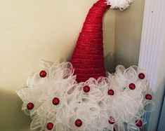 a red and white christmas hat sitting on top of a basket next to a door