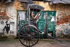 an old horse drawn carriage parked in front of a building with graffiti on the walls