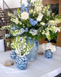 blue and white flowers in vases on a table