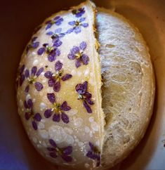 a loaf of bread with purple flowers on it sitting in a bowl filled with water