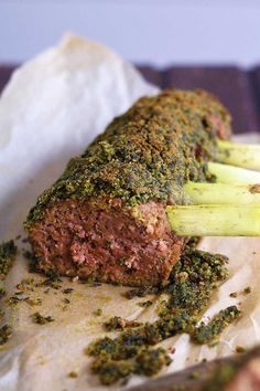 a meatloaf with broccoli and spices on it sitting on a piece of parchment paper