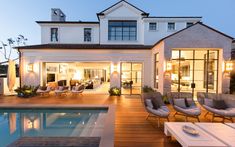 a house with a pool in front of it and chairs around the pool area at night