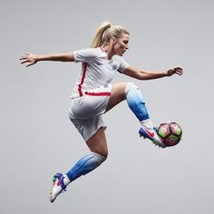 a female soccer player is jumping in the air with her foot up and holding a ball