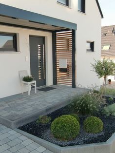 a white chair sitting on top of a patio next to a tree and shrubbery