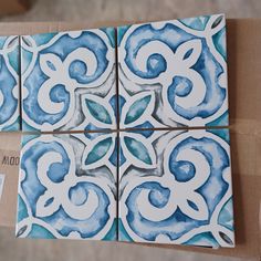 four blue and white tiles sitting on top of a cardboard box