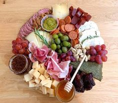 a platter filled with meats, cheeses and other foods on top of a wooden table