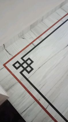 a white marble wall with black and red lines on the bottom, and an orange line in the middle