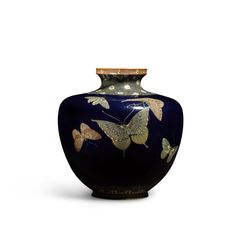 a blue vase with butterflies painted on the side and gold trim around the top, sitting against a white background