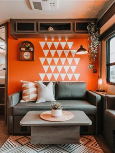 a living room with an orange wall and black leather couch in front of the coffee table