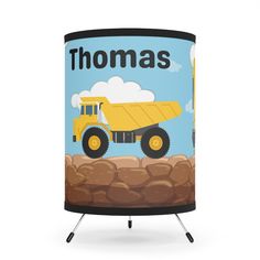 a lamp shade with a yellow dump truck on it's side and the words thomas written