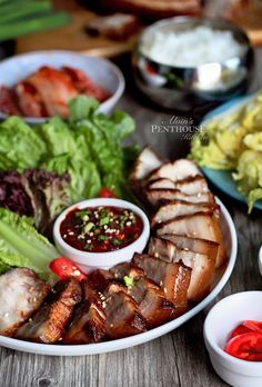 a plate filled with meat and vegetables next to bowls of sauces on a table