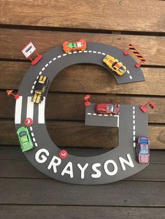 a wooden sign with cars on it and the letter e is for grayson's