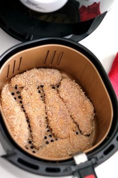 some kind of food in a black container on a white counter top next to a red towel