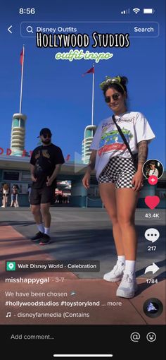 two people walking down the street in front of a building with hollywood studios on it