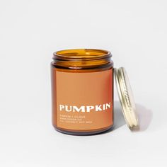 a pumpkin candle with a lid on a white surface next to a jar of wax