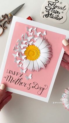 a person holding up a card that says happy mother's day with flowers on it