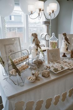 a table topped with lots of desserts and candies on top of a white table cloth