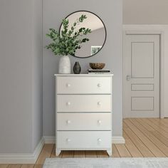 a white dresser sitting in front of a mirror on top of a hard wood floor