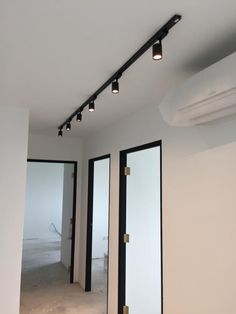 an empty room with three black doors and four lights on the ceiling in front of them