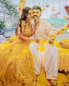 a man and woman sitting on top of a yellow bench covered in confetti