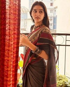 a woman standing in front of a window with her hand on her hip and looking at the camera