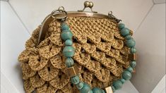 a purse with blue beads on it sitting on top of a white table next to a wall