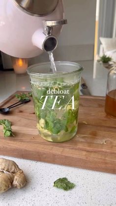 a cup filled with green tea sitting on top of a wooden cutting board