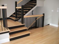 an empty room with wooden floors and black banisters on the wall, in front of a staircase