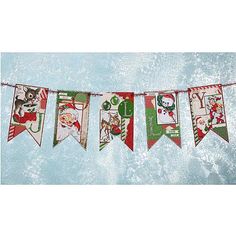 a christmas banner hanging from a line with santa and snowmen on it's sides