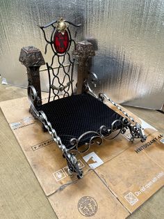 a bed made out of metal and chains on top of some cardboard with a red light in the background