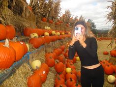 a woman taking a selfie in front of pumpkins