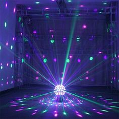 an empty room with purple and green lights on the walls, and a disco ball in the center