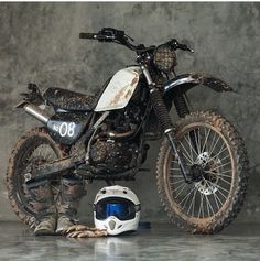 a dirt bike parked next to a helmet on the ground