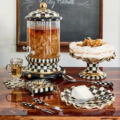 a table topped with plates and cups filled with food next to a chalkboard sign