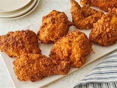 some fried food on a white plate next to a blue and white striped dish towel