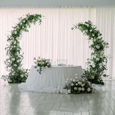 a table with white flowers and greenery on it is set up for a wedding