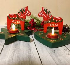 two small candles are sitting on top of some wooden boards, decorated with red and green decorations