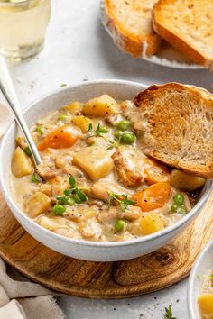 a bowl of chicken and vegetable soup with two slices of bread on the side