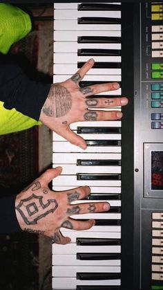 two hands with tattoos are playing the piano